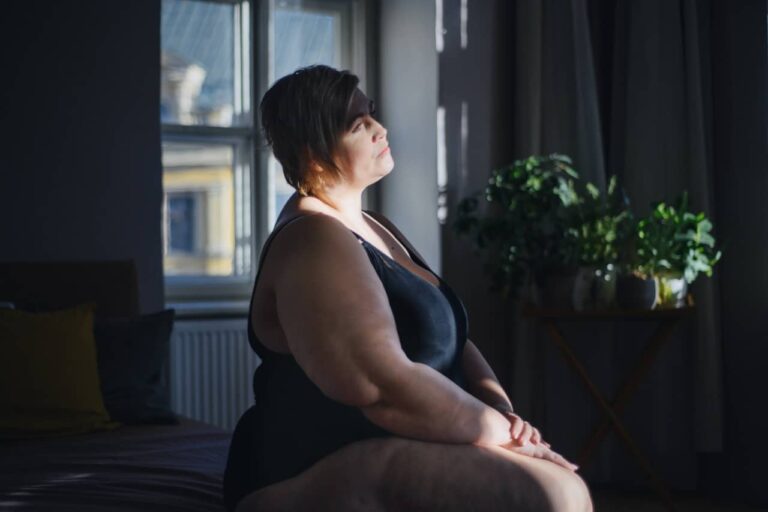 Depressed woman daydreaming and looking out the window at home