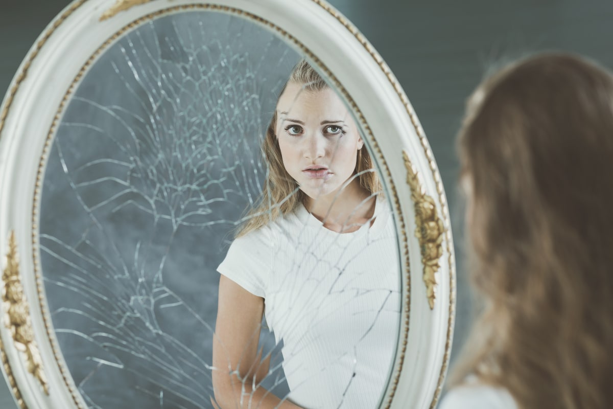 Woman staring into a mirror and understanding that she has self-destructive BPD