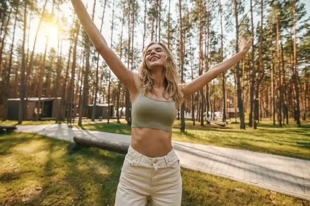 Happy young blonde woman with her eyes closed and arms stretched out upwards. she looks free