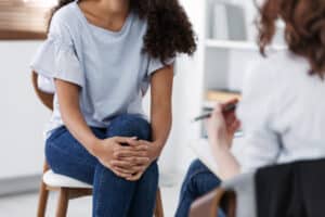 girl sitting across from therapist with her legs crossed in psychotherapy for her OCD