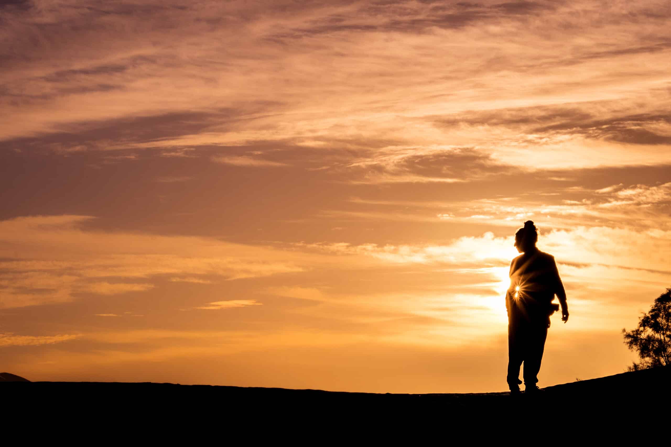 Silhouette of unrecognizable person standing in sunset light.